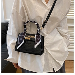 Detail of black faux crocodile skin handbag with heart print scarf and gold buckle
