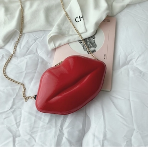 Detail of red glossy patent leather lip-shaped crossbody bag with gold chain strap