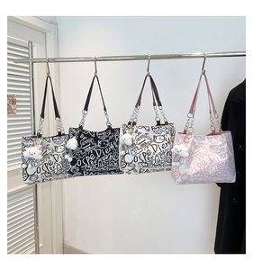 Dettaglio delle borse tote con stampa graffiti, catene metalliche e charm a nuvola