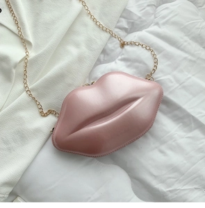 Detail view of pink lip-shaped crossbody bag with glossy finish and gold metal chain