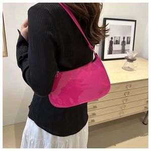 Detalle del bolso hobo de charol rosa con cremallera dorada mostrado en modelo