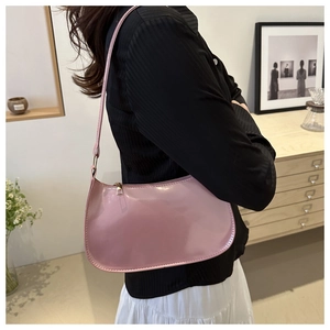 Bolso hobo rosa de charol brillante lucido por una modelo en un interior moderno
