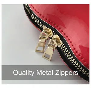 Detail of red patent leather heart bag showing high-quality gold dual zipper hardware