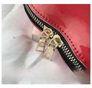 Detail of red patent leather heart bag showing high-quality gold dual zipper hardware