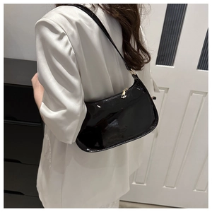 Detalle de bolso de hombro en charol negro brillante con cremallera dorada fina