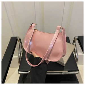 Detalle de bolso de hombro en charol rosa con cremallera dorada y un diseño minimalista