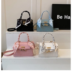 Detailed view of four small square crossbody bags with crocodile texture and silk scarves