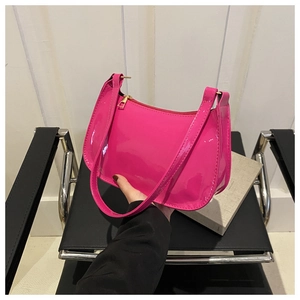 Detalle del bolso de hombro en charol rosa fucsia con acabado brillante y cremallera dorada