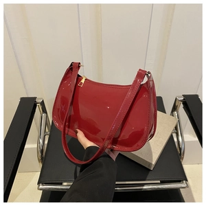 Detalle de bolso baguette en charol rojo con acabado brillante y cremallera dorada
