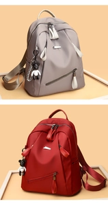 Detail of waterproof nylon backpacks in grey-purple and red colors with bear pendants