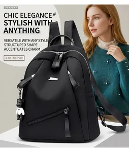 Detail of black nylon backpack with silver zippers, metal logo plate and bear charm