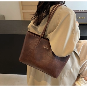 Detailed view of dark brown textured faux leather shoulder bag with metallic logo