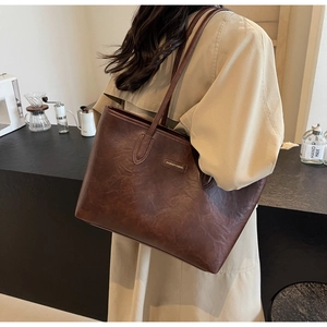 Detail of coffee brown large tote bag with retro leather texture and fashion logo