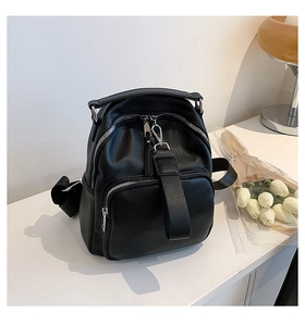 Detail of black pebbled leather backpack with silver zippers and elegant tulip decor