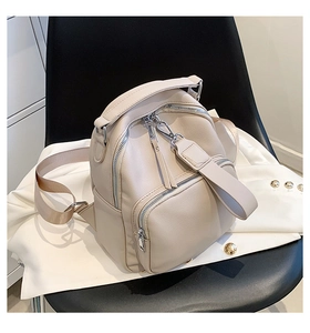 Detailed close-up of a beige faux leather mini backpack placed on a stylish blazer