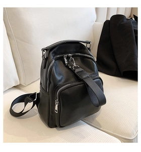 Detail of black pebbled leather backpack with silver zippers and multiple compartments