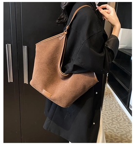 Detail of dark brown corduroy tote bag showing vertical texture and leather logo tag