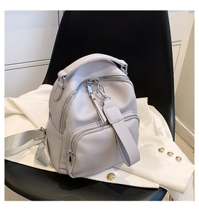 Detail view of mini grey PU leather backpack with silver hardware on a casual blazer
