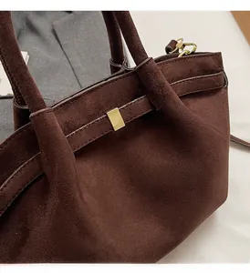 Detail der dunkelbraunen Handtasche aus Wildleder mit goldener Schnalle und stabilem Griff