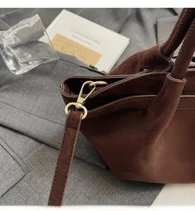 Detailansicht des goldenen Metallhakens und braunen Wildlederriemens einer Beuteltasche