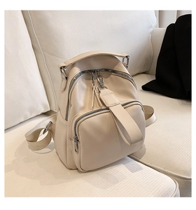 Close-up of beige lychee grain faux leather backpack on a sofa with silver hardware