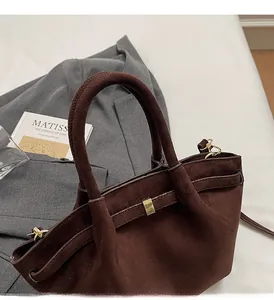 Detailansicht der dunkelbraunen Wildledertextur und der goldenen Metallschnalle der Tasche