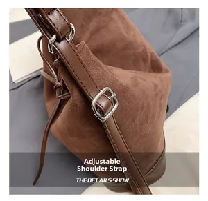 Detail of adjustable leather strap and silver buckle on a brown suede bucket bag