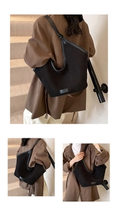 Detailed close-up of large black canvas tote bag with wide leather straps and sleek brand logo