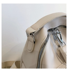 Detailed macro view of beige pebble grain leather texture and silver hardware zippers