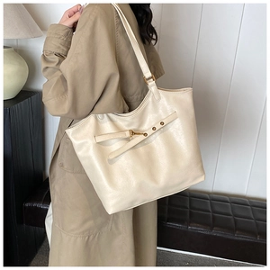 Close-up of cream matte tote bag with shoulder strap worn by model for daily commute