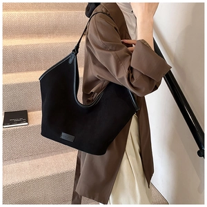 Large black matte shoulder tote bag with leather trim shown on model in urban setting