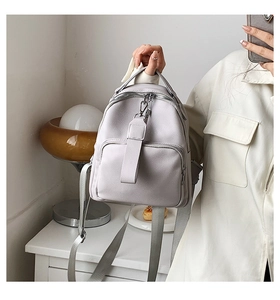 Detail shot of light gray faux leather mini backpack with textured litchi grain finish
