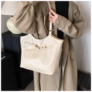 Detail of high-gloss cream PU leather tote bag with metal eyelets and lobster clasp