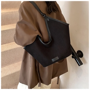 Detail of black tote bag with leather trim and debossed logo on a minimalist base
