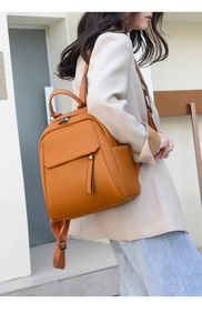 Detail of orange-brown soft leather backpack with litchi texture and metal zipper
