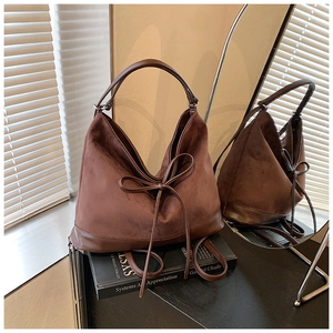 Deep brown matte faux leather tote bag with elegant bow tie decoration on a book