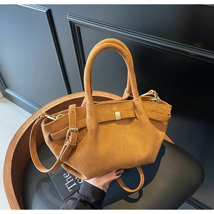 Details einer braunen Wildleder-Handtasche mit strukturierter Oberfläche und Goldteilen