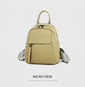 Detail view of olive green mini backpack featuring lychee grain texture and zippers