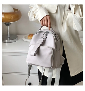 Detailed view of light grey pebble leather backpack with double zippers and webbing straps