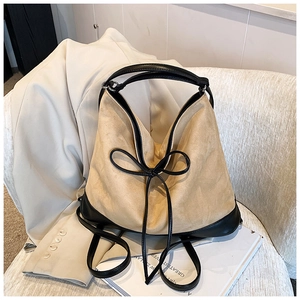 Large khaki suede and black leather hobo bag with bow detail on a stylish sofa