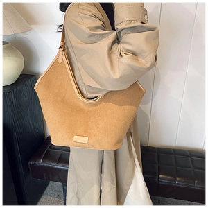 Detail of the corduroy hobo bag texture and leather trim worn by a model in a minimalist room