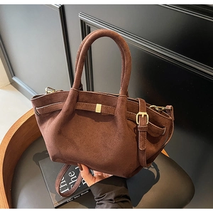 Nahaufnahme braune Handtasche aus Wildleder mit goldener Schnalle und verstellbarem Gurt