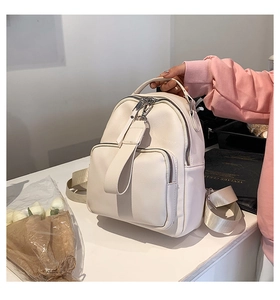 Detail of cream white pebbled leather backpack showing wide straps and silver zippers