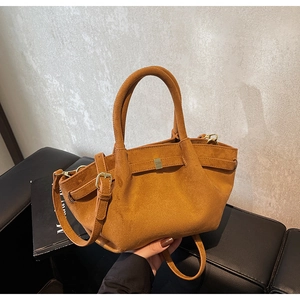 Detail einer braunen Wildleder-Beuteltasche mit Seitenfalten und goldener Quadratschnalle
