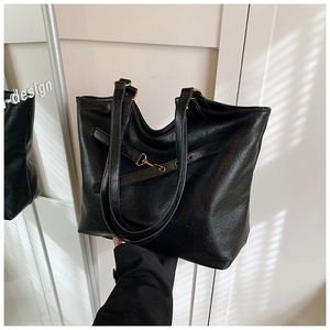 Close-up of black oil-wax faux leather tote bag with gold buckle detail and long straps