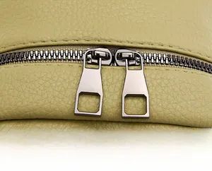 Detail view of smooth dual metal zippers on a soft green pebbled leather backpack