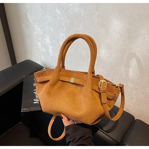 Details einer braunen matten Wildlederhandtasche mit Goldschnalle und Trageriemen