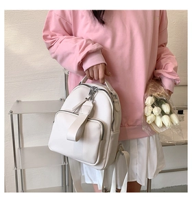 Mini white PU leather backpack with lychee texture and dual zippers held by a model