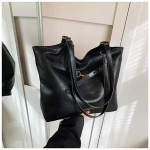 Detail of retro black tote bag with litchi texture and golden metal buckle accents