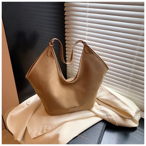 Close-up of khaki tote bag with V-shaped opening and leather brand tag on office suit
